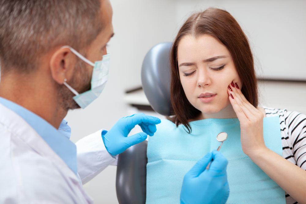 young woman holding her mouth in pain at the dentist