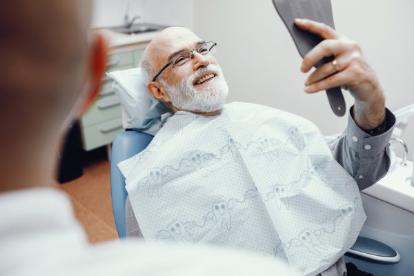 A man sits in the dental chair and admires his smile following a fluoride treatment.